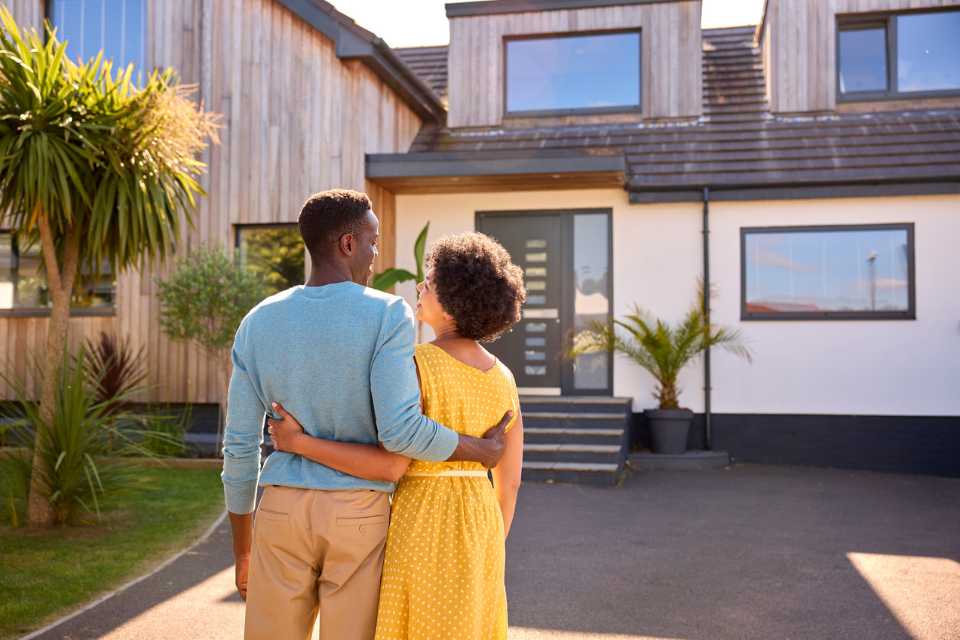 African American couple standing in front of house