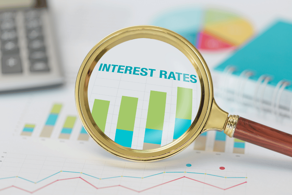 Image shows a magnifying glass and calculator on interest rate graph.