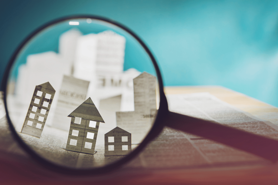 Magnifying glass in front of an open newspaper with paper houses