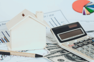 Image shows a miniature house with money and a chart