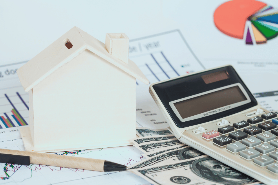 Image shows a miniature house with money and a chart