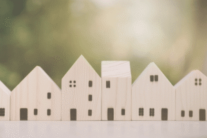 Image shows housing market concept with a row of wooden model houses