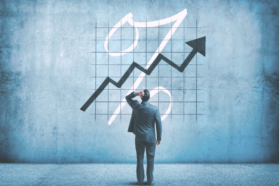 Image shows a businessman placing his hand on his head as he is perplexed by a chart indicating rising interest rates